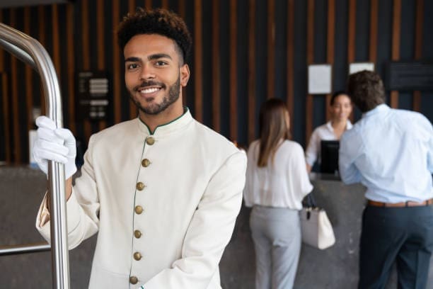 A hotel porter handling guest luggage, representing the white-glove service included in concierge-level guest management.