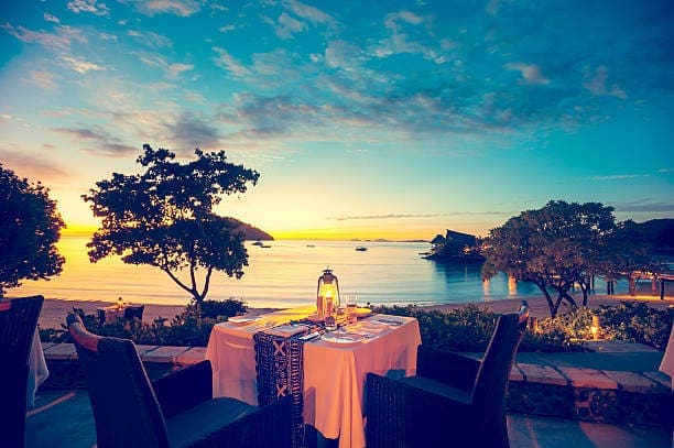 A private, candlelit anniversary dinner for two at sunset, overlooking the ocean.