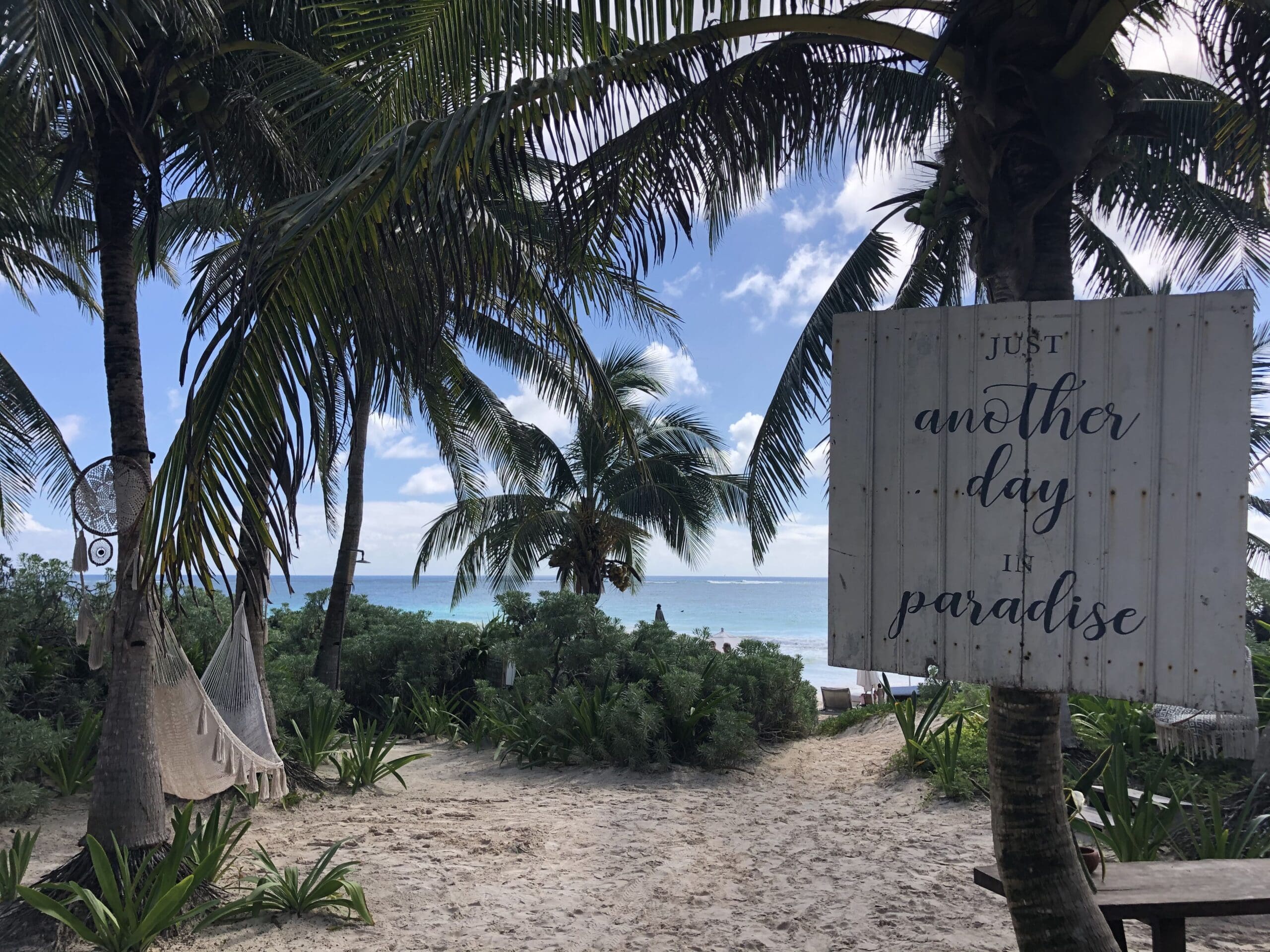 Tropical beach view in Tulum, Mexico with palm trees and a hammock, curated by Jennie B Travels, an expert Caribbean travel advisor.